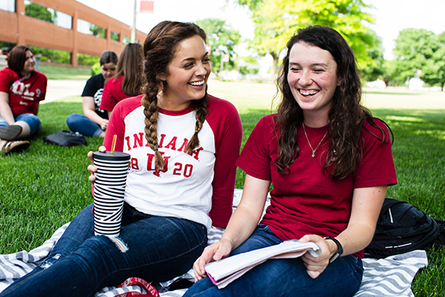 Two students studying outside on the grass